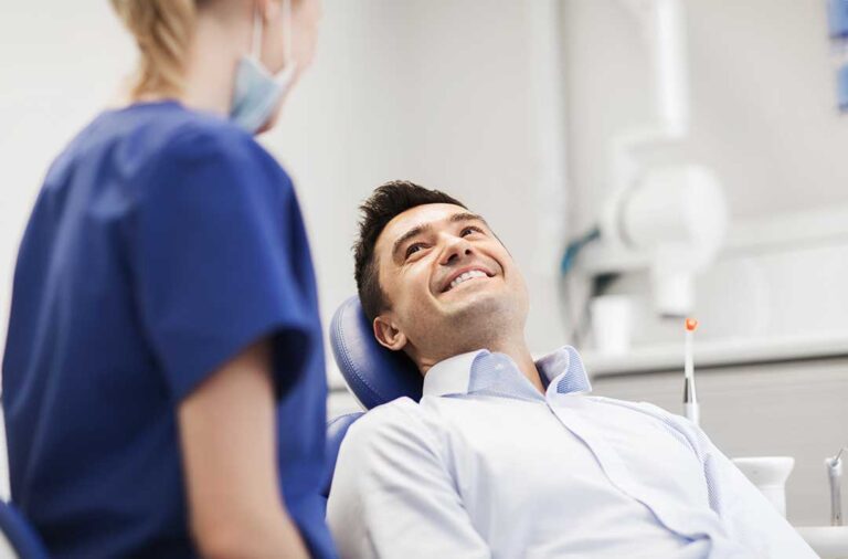 A young child sitting on a parent's lap while a dentist gently examines the child's teeth.