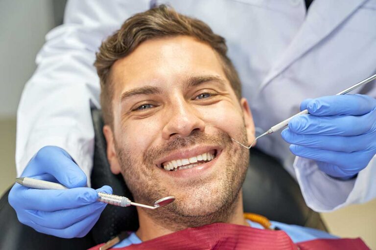 A close-up of a person showing a chipped front tooth while touching their mouth gently.